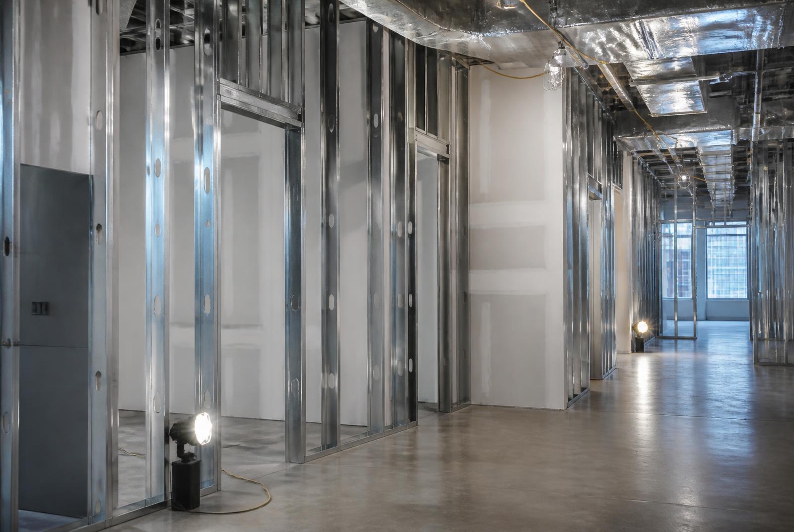 Interior renovation in progress with organized metal stud framing and polished concrete floor